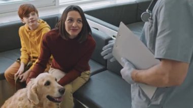 Golden Retriever 'ın bayan sahibi ve 10 yaşındaki oğlunun profesyonel danışmanlık için veteriner kliniğini ziyaret ederken orta açıdan çekilmiş bir fotoğrafı.