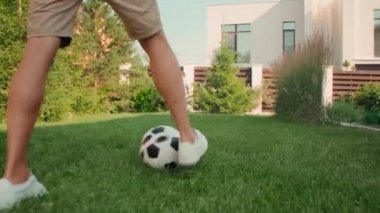 Modern yetişkin bir adamın güneşli bir yaz gününde 8 yaşındaki oğluyla futbol oynayıp arka bahçede eğlendiği el kamerasıyla çekilmiş bir fotoğraf.