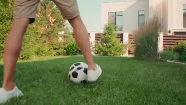 一緒に楽しい裏庭で晴れた夏の日にかわいい8歳の息子と一緒にサッカーをしている現代の若い大人の男の手によるローアングルショット — ストック動画