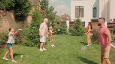 Altı nesildir arka bahçede badminton oynayıp birlikte eğlenen büyük, çoklu nesil bir ailenin tam çekimleri.