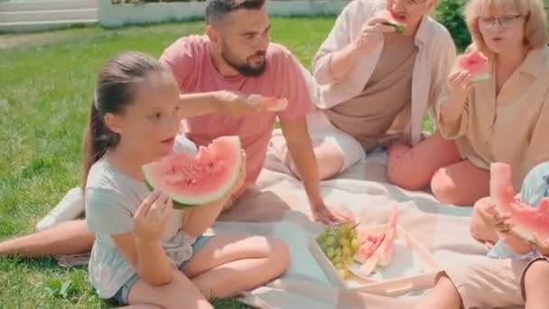从上到下 六代多代轻松的一家人在院子里坐在草地上聊天 吃西瓜 度过了夏天 — 图库视频影像