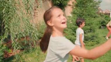 Güneşli yaz gününde aile fertleriyle dışarıda badminton oynayan neşeli 10 yaşında bir kız çocuğu.