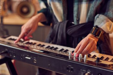 Müzisyenin bir sentezleyici çalıp konserde sahne aldığı yakın plan.