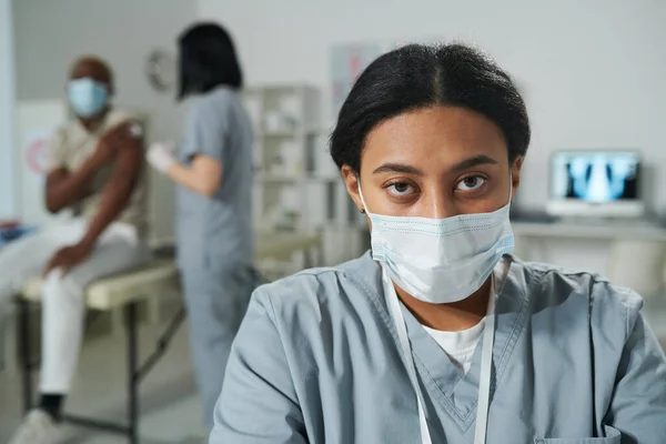 Joven Clínica Femenina Raza Mixta Seria Con Uniforme Máscara Protectora — Foto de Stock