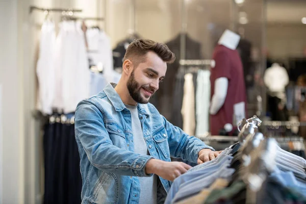 Junger Bärtiger Mann Wählt Neue Kleidung Auf Dem Regal Einkaufszentrum — Stockfoto