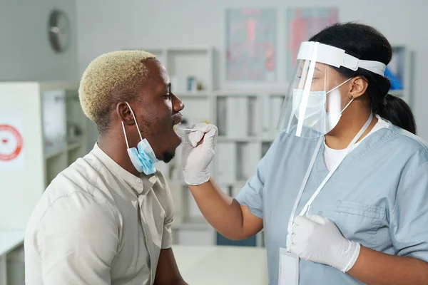 Молодий Пацієнт Африканець Відкритим Ротом Сидить Перед Медсестрою Змішаної Раси — стокове фото