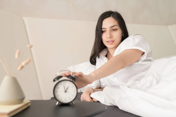 Jovem Linda Fêmea Pijama Branco Pressionando Botão Despertador Enquanto Sentado — Fotografia de Stock