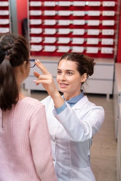 Jovem Oftalmologista Feminina Whitecoat Sentado Agachamentos Frente Menina Enquanto Colocando — Fotografia de Stock