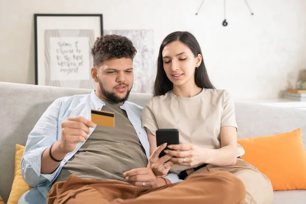 年轻的黑发女人一边带着信用卡 一边用智能手机向丈夫展示美味的食物 一边去网吧点午餐 — 图库照片