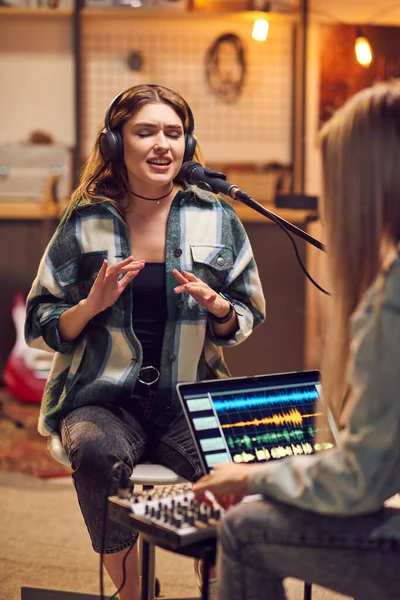 Stüdyoda Dizüstü Bilgisayarla Çalışan Meslektaşının Önünde Şarkı Söyleyen Kulaklıklı Genç — Stok fotoğraf