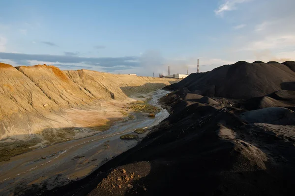 工業用パイプや曇りの空を背景に 川の汚れた水と丘や山に囲まれた有毒土壌を持つ放棄されたエリア — ストック写真