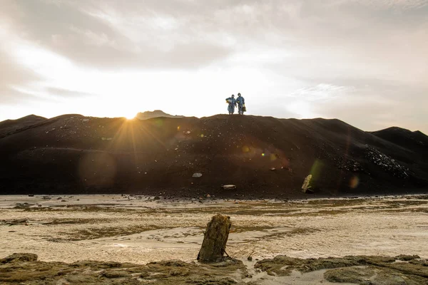 現代の研究者の小さなシルエット丘の上に立って灰色の曇りの空に対して日没で汚染された水の流れを下に — ストック写真