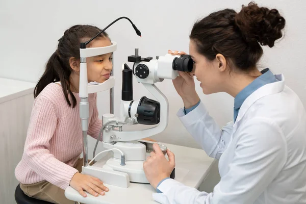 当代年轻眼科医生在诊所用医疗器械检测可爱小女孩视力时的研究 — 图库照片