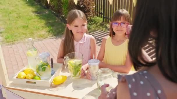 在炎热的夏天 一群可爱的10岁小女孩正站在露天小摊上向顾客微笑 向她们兜售柠檬水 — 图库视频影像