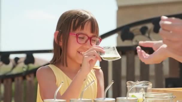 かわいいです10歳の女の子販売新鮮な自家製レモネードで屋外に立つお客様に熱い夏の日にスタンド — ストック動画