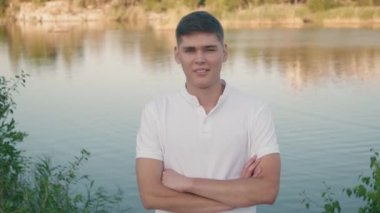 22 yaşındaki PAN 'ın göl kıyısında kolları çapraz duran ve kameraya bakan portresi.