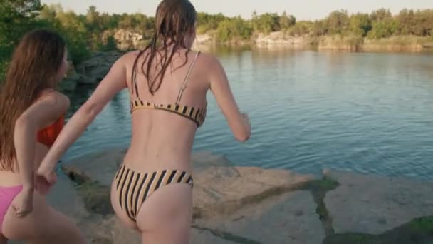 スローモ追跡ショットの若い女性で水着で実行し 湖に崖からダイビング — ストック動画