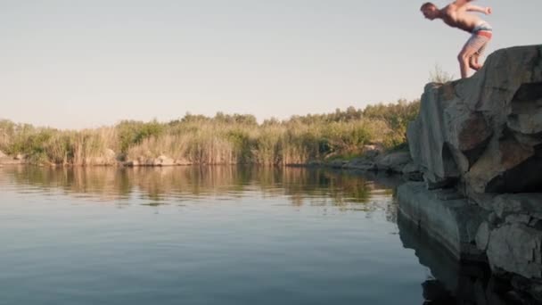 Pan Slowmo Bezkoszulkowego Młodego Człowieka Skaczącego Klifu Nurkującego Jeziorze Latem — Wideo stockowe