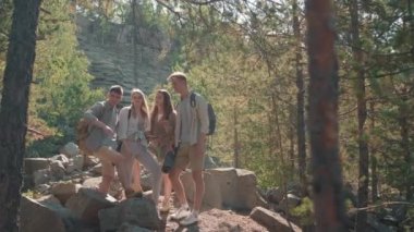 Güneşli bir yaz gününde ormanda durup cep telefonundan haritaya bakan sırt çantalı bir grup genç arkadaşın fotoğrafını çekiyorum. Konuşuyorlar ve talimatlara bakıyorlar.