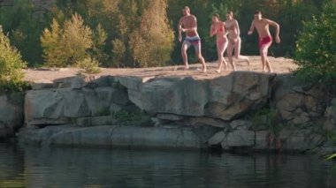Mayo giymiş bir grup genç arkadaş küçük bir uçurumdan göle atlayıp koşuyorlar. Bir kadın korkuyor ve kıyıda kalıyor.