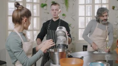 Aşçılık yüksek lisansı yaparken yemek pişirmeyi öğrenen küçük bir grup insanın orta ölçekli çekimi. Kadın hamur yapmak için stand-mix kullanıyor.