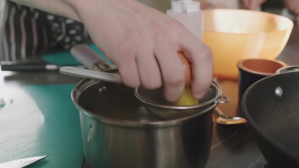 料理のマスタークラス中に白と黄身を分離するための鍋に設定ストレーナーに卵をクラック認識できない男性シェフのクローズアップ — ストック動画