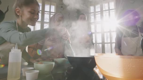 料理の達人クラスの間にスモーキーなキッチンで一緒に人々と若い男性シェフの料理の小さな喜びのグループのスローモーション中のショット — ストック動画