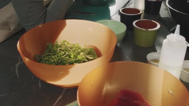 在阳光下 在烹调桌上用鲜绿色的牛油果叶把塑料橙色碗关上 — 图库视频影像
