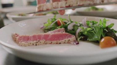 Dilimlenmiş ton balıklı bifteği taze sebze salatasıyla servis eden tanınmamış şefe yakın çekim.