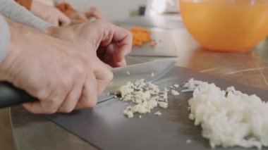 Yemek kursu sırasında teknede sarımsak ve soğan doğrayan tanınmayan erkek elleri yavaş çekimde.