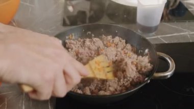 Yavaş çekimde bir adamın et ve sebzeleri kızartıp kızartma tavasına karıştırdığı görüntüler.