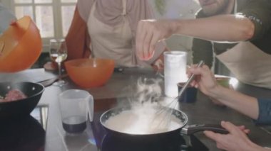 Aşçılık kursu sırasında mutfakta birlikte yemek pişiren ve lezzetli kremalı beşamel sosu yapan tanınmayacak kadar küçük bir grup insanın yavaş çekimleri.