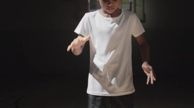 Afrika kökenli Amerikalı küçük bir çocuğun iç saha basketbol sahasında top sürerken yavaş çekilen el kamerası görüntüleri.