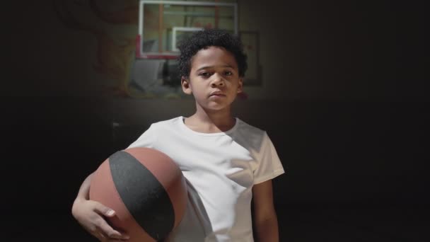Portrétní Záběr Afroamerického Chlapce Basketbalovým Pózováním Pro Kameru Tmavém Vnitřním — Stock video