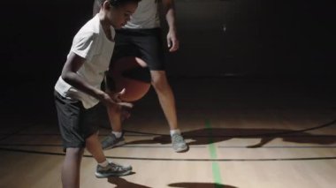 Siyahi erkek basketbolcunun kapalı sahada top sürmeyi öğretirken elde çekilmiş bir fotoğrafı.