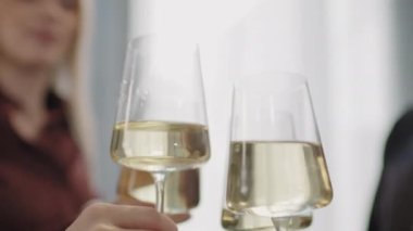 Beyaz şarap kadehleriyle kadeh kaldıran tanınmayan gençlerin yakın çekimleri.