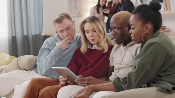 Genç Erkek Kadınların Birlikte Kanepede Oturup Tablete Bakarken Konuşmalarının Pan — Stok video