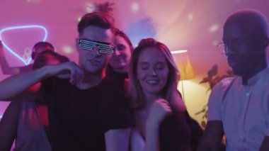 Kameranın önünde mor ışıkla dans eden bir grup gencin el kamerasıyla çekilmiş yavaş çekimi.