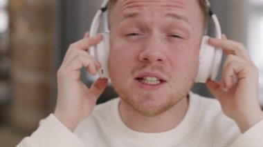 Kulaklıklı genç adamın kamera önünde dans edip şarkı söylediği yakın plan bir çekim.