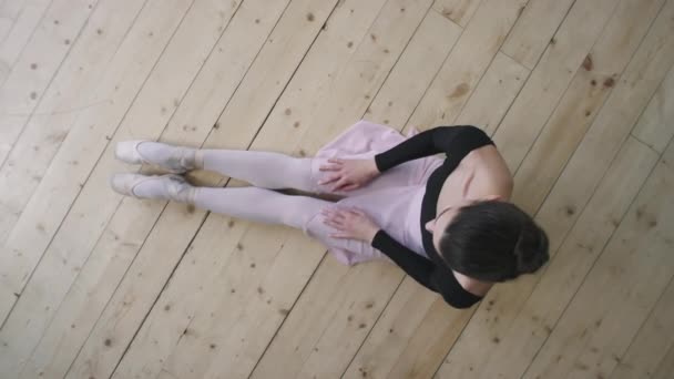 身穿黑色紧身衣 敞着背坐在芭蕾舞演播室木制地板上等待上课的年轻而优雅的芭蕾舞演员的头像照片 — 图库视频影像