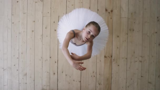 バレエ学校で一人で優雅に踊る白いチュチュのドレスで優雅な9歳のバレリーナのトップビューショット — ストック動画