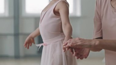 Dans okulunda antrenman yapan kadın eğitmenin yardımıyla küçük güzel bir kızın bale pozisyonunda durmayı öğrenmesini çekiyoruz.