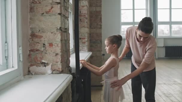 在阁楼式舞蹈课上教可爱小女孩跳芭蕾的年轻女芭蕾教练中的一个镜头 — 图库视频影像