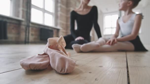 在阁楼风格的舞蹈学校接受背景训练后 与年轻女子和小芭蕾舞演员在木制地板上互相交谈的尖皮鞋服装 — 图库视频影像