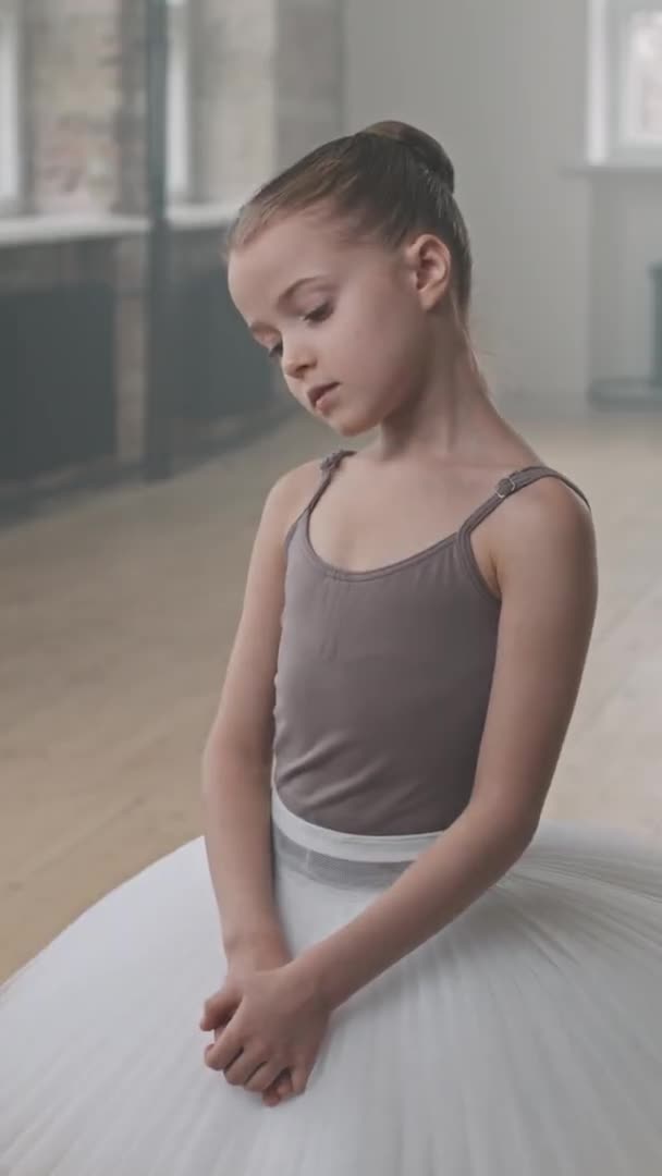 身着白色燕尾服的漂亮的9岁芭蕾舞演员站在舞蹈课上对着镜头微笑的立面媒体画像 — 图库视频影像