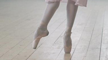 Dans stüdyosunun ahşap zemininde dans eden, sivri pabuçlu, tanınmayan balerinlerin düşük kesiminden çekimleri.