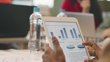 Tanımlanamayan işadamının tablet tutarken ve toplantı sırasında mali belgeleri incelerken yakın çekim