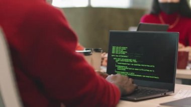 Tanımlanamayan adamın orta bölüm PAN 'ı ofisinde oturuyor ve dizüstü bilgisayarında kodluyor.