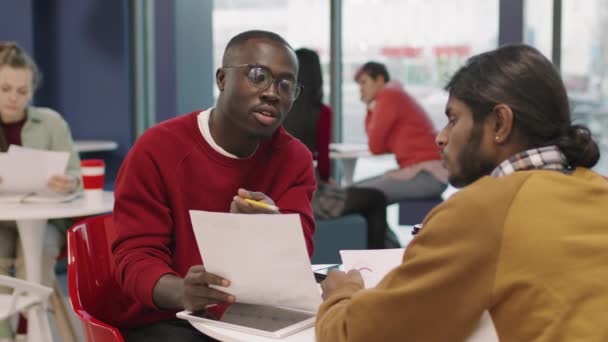 中には アフリカ系アメリカ人の若いビジネスマンやインド人の同僚がオフィスのカフェテリアに座り 文書について議論した — ストック動画