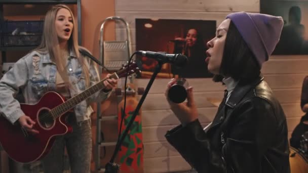 미디엄 느림보의 매력적 보컬리스트가 마이크로 노래하는 그녀의 동료들 스튜디오에서 기타와 — 비디오